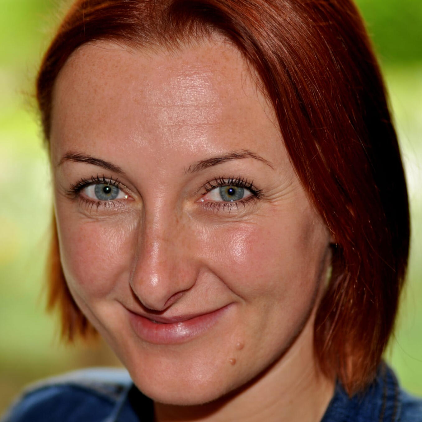 Portret uśmiechniętej kobiety o rudych włosach i niebieskich oczach; instruktorka w Modlimowie.